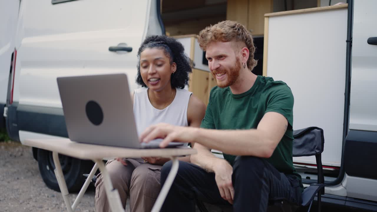 Couple using a laptop outside their van