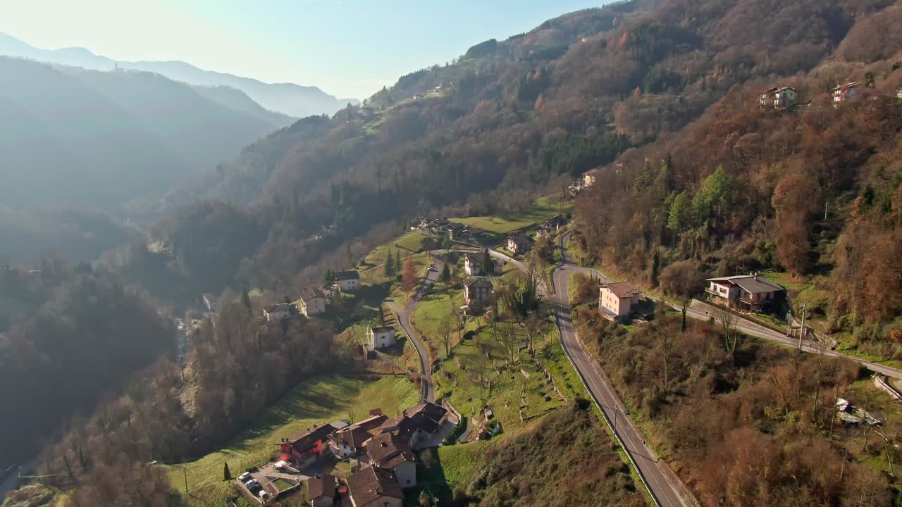 이탈리아의 고풍스러운 산악 마을 위를 날아다니는 드론 영상, 전형적인 가을 날의 가을 색과 시골적인 매력을 보여줍니다.