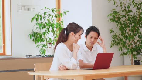 asian couple using the laptop at home