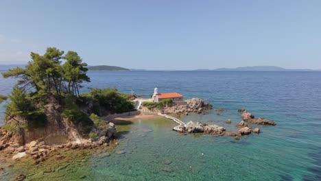 drone footage revealing the isolated st. nikolaos island at ellinika beach, north evia, showcasing its peaceful surroundings and the crystal-clear coastal waters