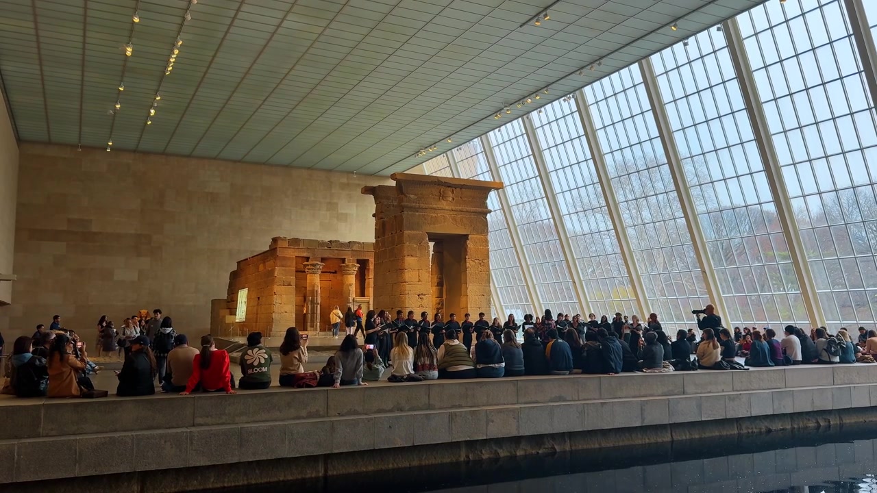 New York, USA, 15 marzo 2026: Antico tempio egizio in una moderna sala museale con grande finestra. Il Tempio di Dendur all'interno del Metropolitan Museum of Art con riflesso in una vasca d'acqua e visitatori