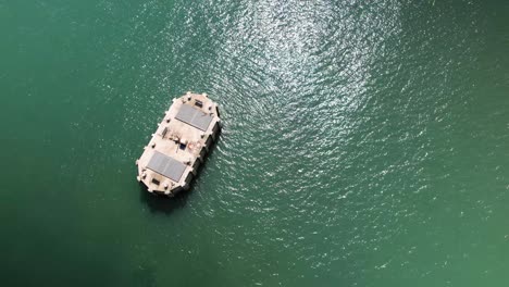 Aerial-Birdseye-view-above-Fawley-power-station-cooling-water-outlet-surrounded-by-shimmering-sunlit-emerald-ocean