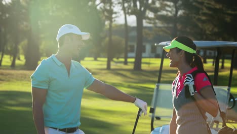 happy couple interacting with each other while playing golf