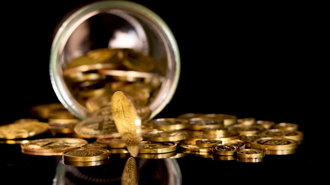 Gold coin spins upright among scattered coins, glass jar, dramatic lighting, black reflective background