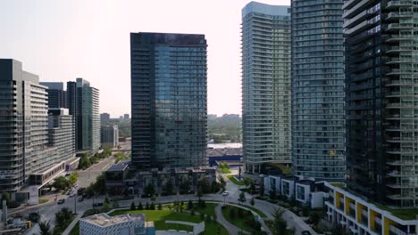 Sun-shining-through-glass-condominium-development-buildings-and-urban-park-during-morning-sunrise