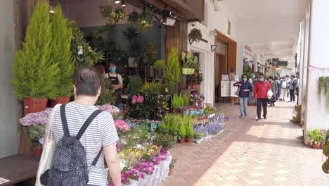 corona virus pandemic, locals visiting wearing protective face masks in hong kong mong kok flower market, known for its large variety of rare flowers and plants.