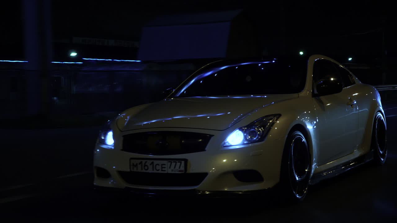 A white car driving on a road at night
