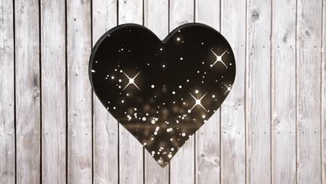animation of starry background over heart shapes hole in grey wooden surface