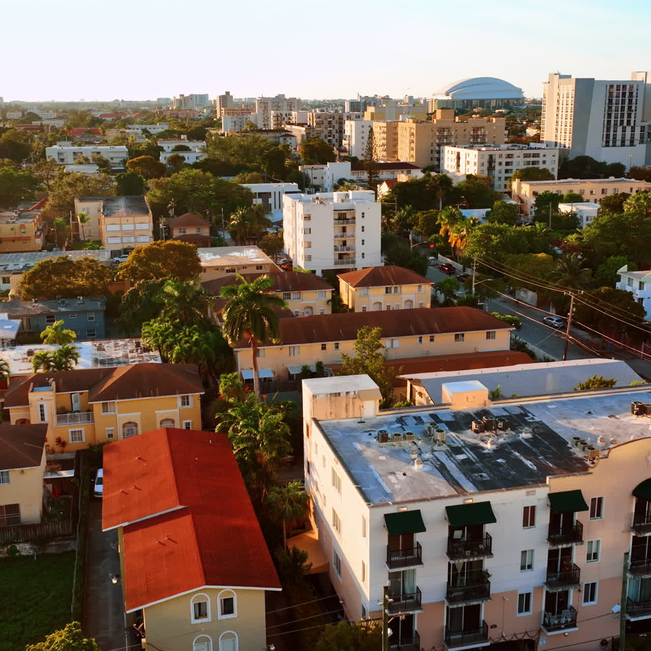 Flight above the houses in sunny Miami. Cozy houses and palm-trees in the residential area of American city.