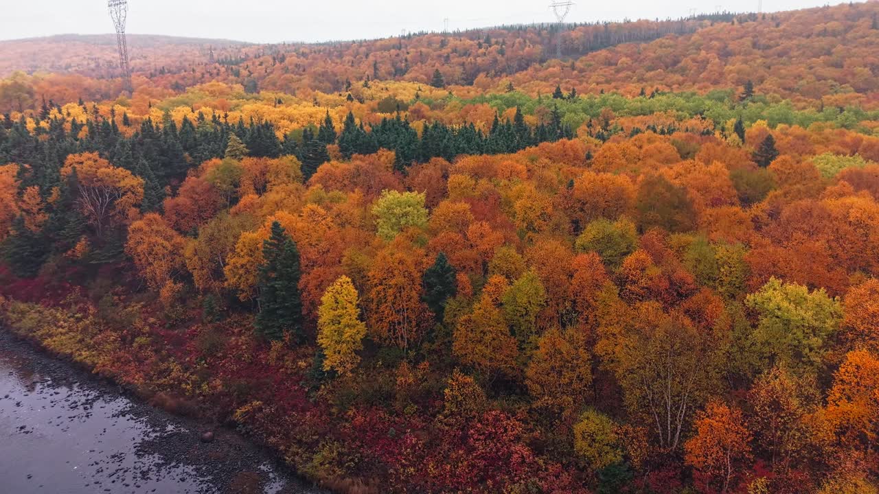 Drone footage shows serene lake reflecting autumn hills with vibrant fall colours