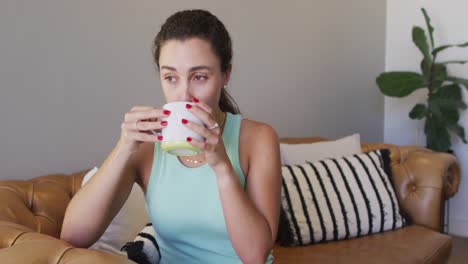 mujer caucásica relajada sentada y bebiendo café en casa