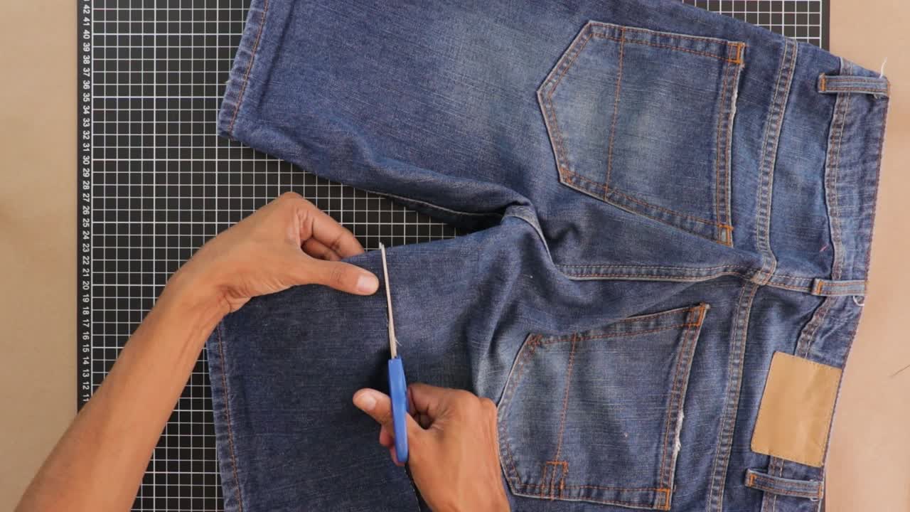 가위로 짧은 바지를 리모델링하고 잘라내는 사람