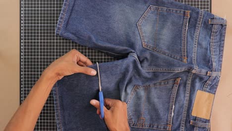 person remodeling and cutting short trousers with scissors