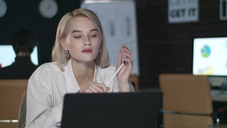 thoughtful business woman looking to laptop screen in dark office interior