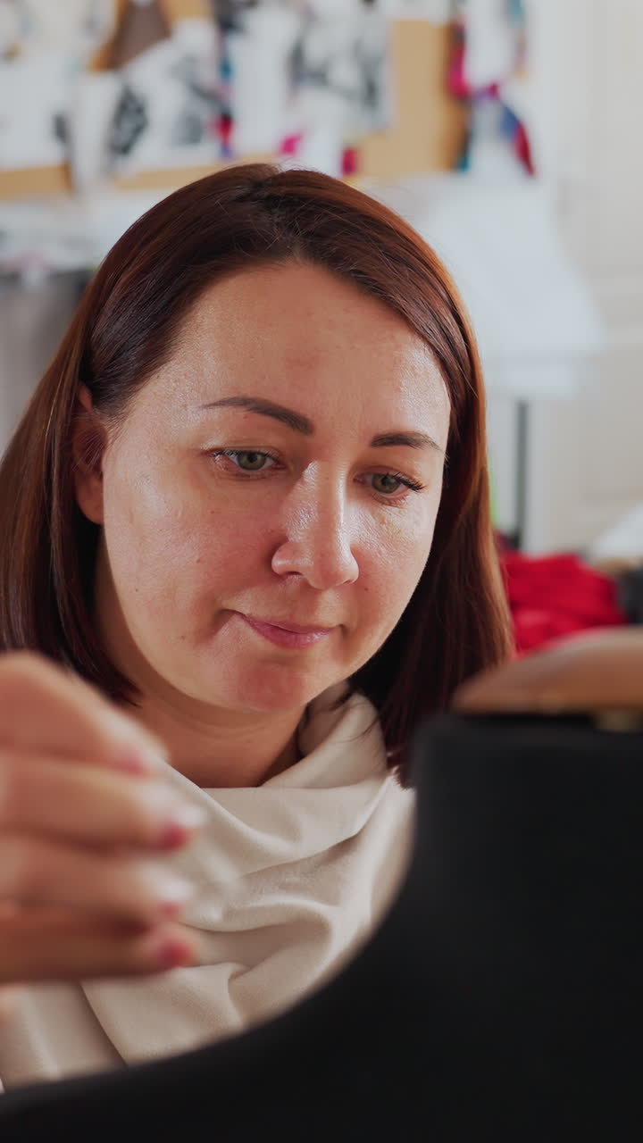 Mujer caucásica maquillándose frente al espejo. Una bloguera de belleza difumina la base, da toquecitos bajo el ojo, comprueba el tono en el cuello y prueba la textura con una esponja bajo una luz interior suave con una expresión de calma y concentración.