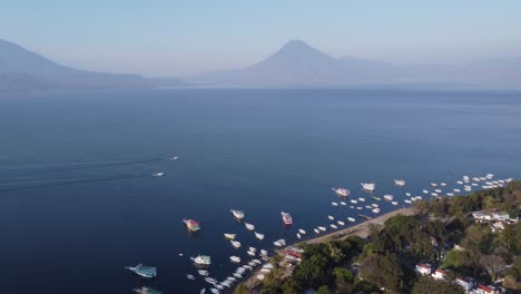 boats line jaibalito shore across lake atitlan from volcano mountain