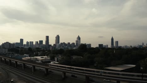 the marta metro train in atlanta georgia passes by in the foreground of a gorgeous aerial shot of downtown atlanta skyline