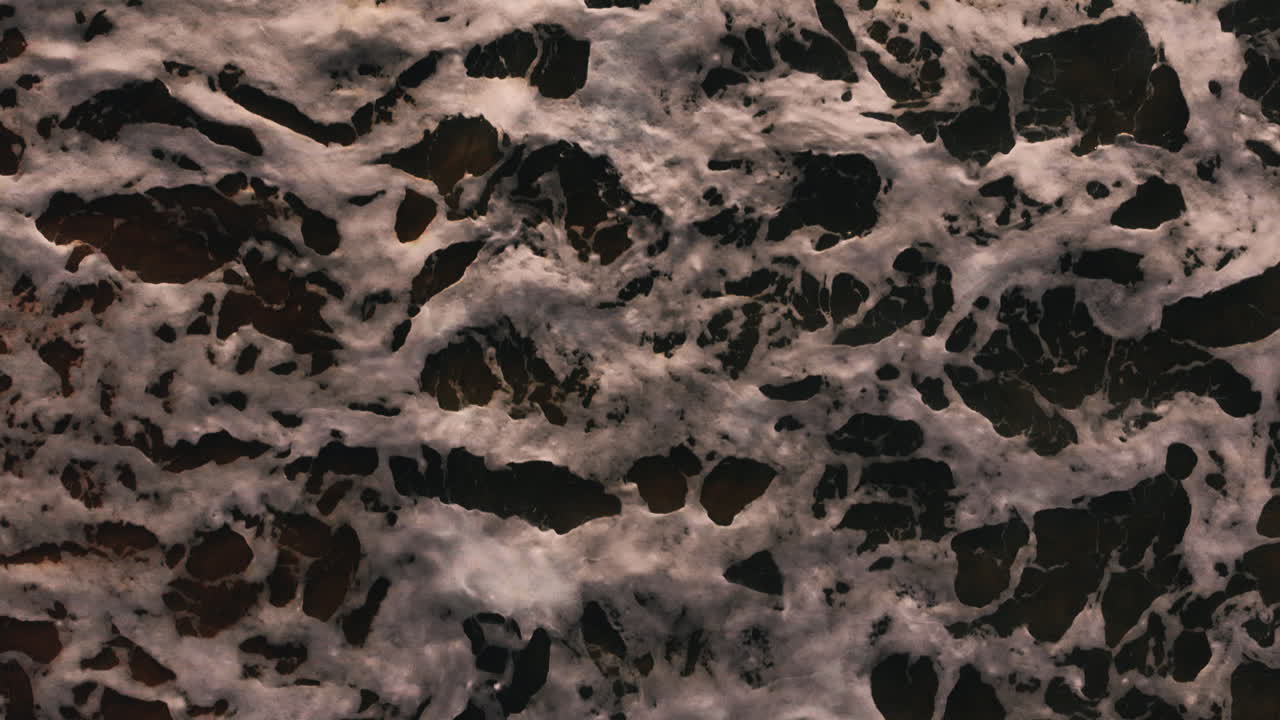 aérea: comienza con una vista del agua volando hacia adelante y inclinando lentamente la cámara para mostrar la playa y los acantilados