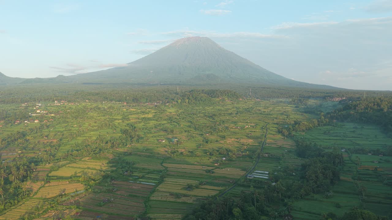 Vista aerea del maestoso vulcano del Monte Agung, circondato da lussureggianti risaie verdi e foresta tropicale durante una splendida alba, ripresa dal punto panoramico Bukit Cinta a Bali