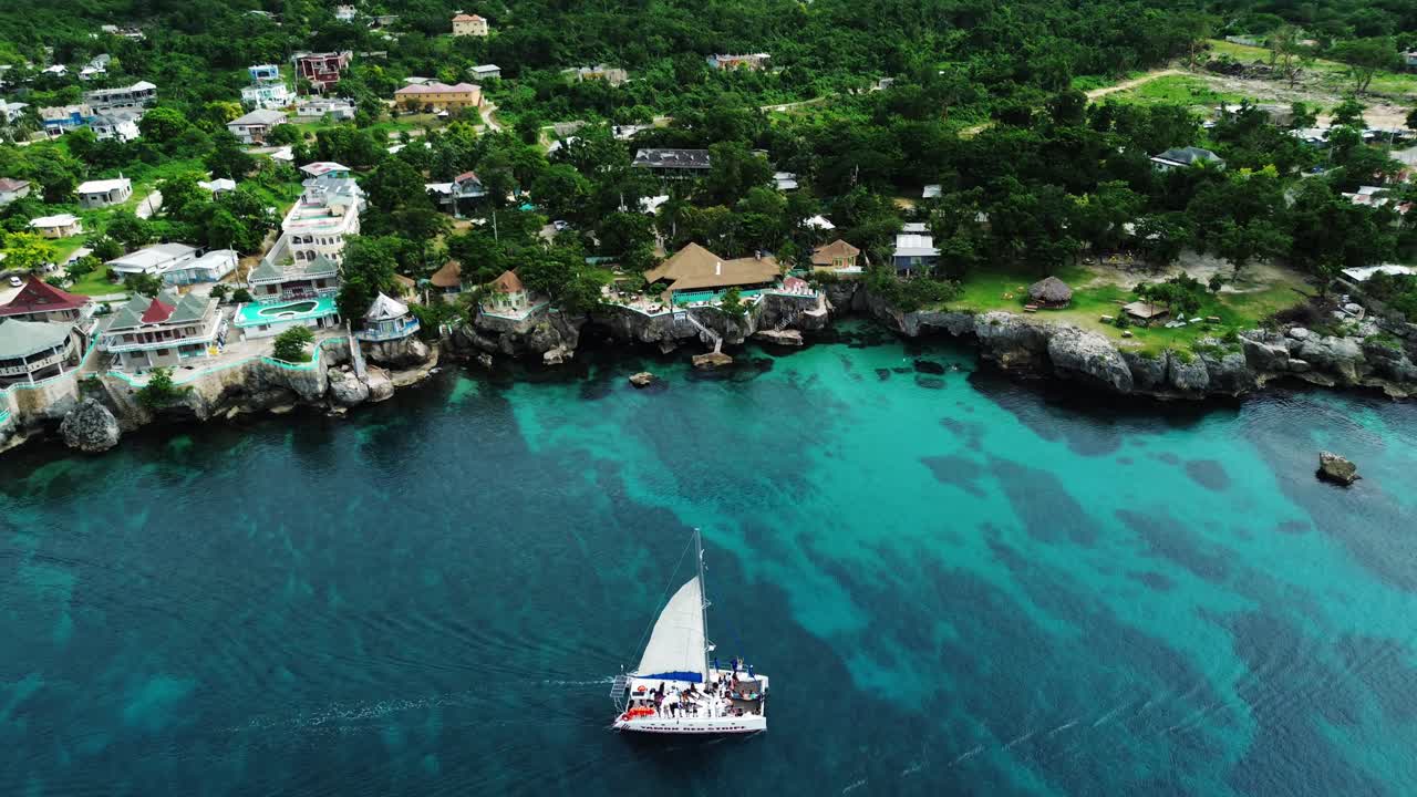Sail Boat in blue turquoise waters sailing along the cliffs.