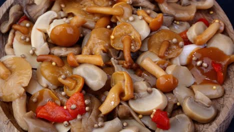 muchos hongos de miel encurtidos salpicados con guisantes de especias giran lentamente en la mesa giratoria.