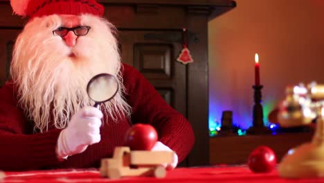 santa claus con lupa inspecciona manzanas en un camión de juguete de madera