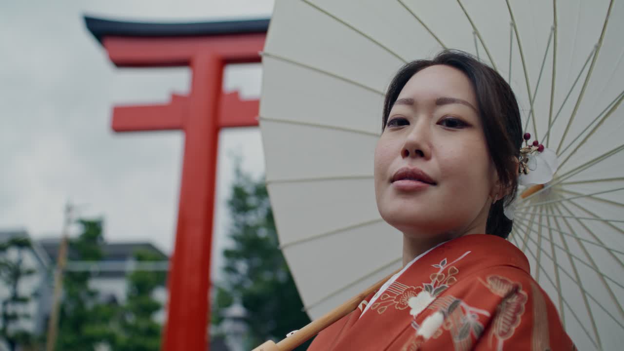 Woman in Kimono with Umbrella in front of Torii Gate