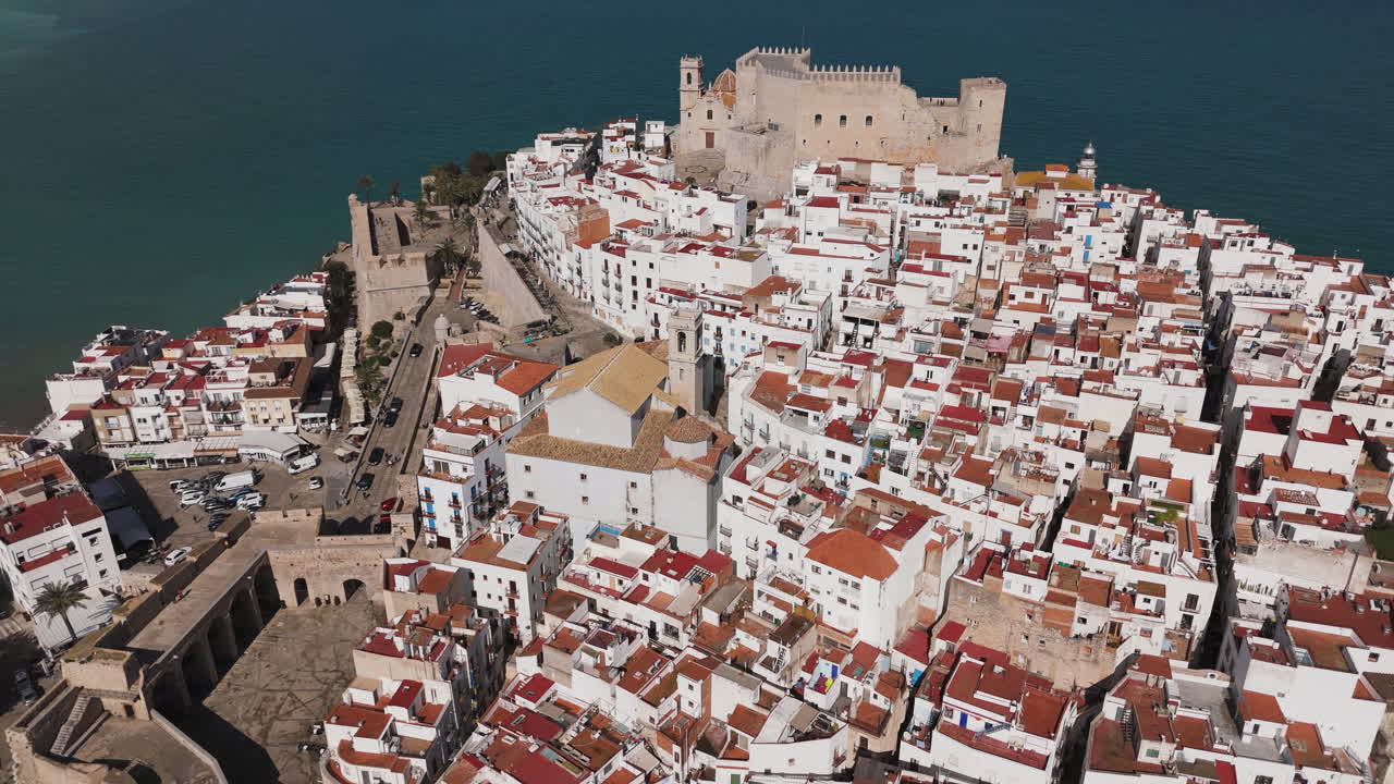 High aerial zoom onto Castell de Peniscola and its surrounding terracotta rooftops and sea