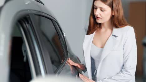 girl in a business suit appreciates the painting of a new car