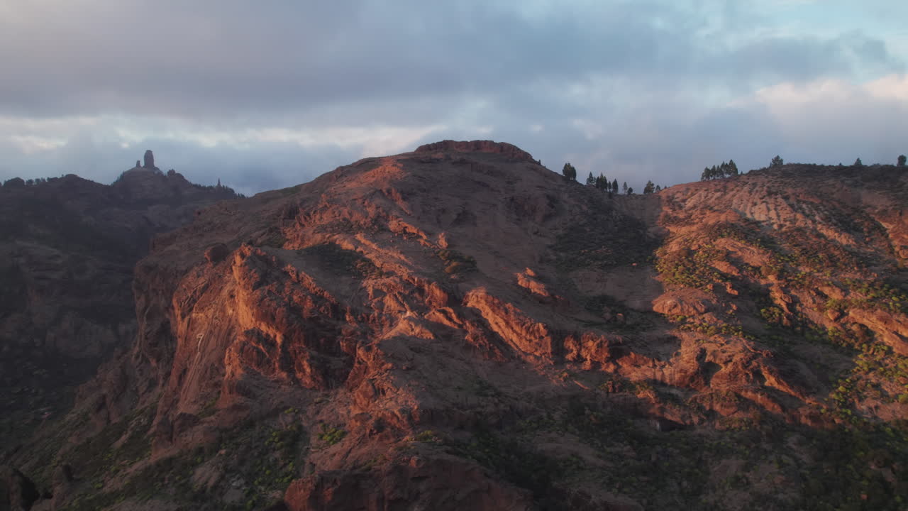 Warm sunlight illuminates Roque Nublo and mountains in Gran Canaria, Canary Islands, Spain