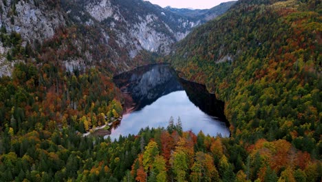 Calm-Topletz-lake-nestled-amidst-colorful-trees-and-majestic-mountains-in-the-fall,-a-body-of-water-surrounded-on-the-shore-of-a-mountain-range