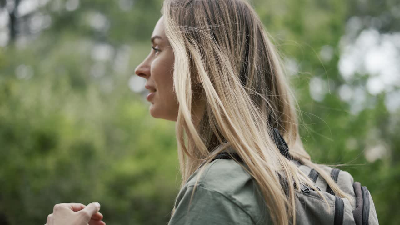 Una donna beve acqua da una bottiglia nel bosco.