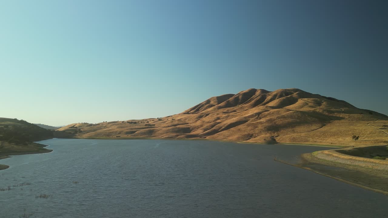 The drone captures the serene beauty of Paicines Reservoir, where calm waters mirror the open sky and scenic terrain.