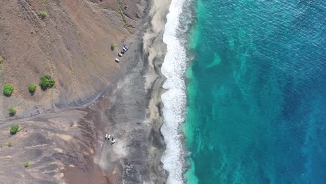 Vista-Aérea-De-Arriba-Hacia-Abajo-Del-Océano-Turquesa-Y-La-Playa-Gris-Vacía-De-La-Isla-Volcánica,-Toma-Aérea-Con-Dron-En-ángulo-Alto