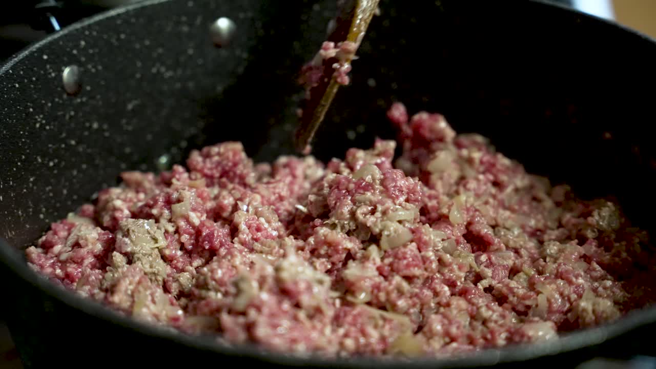 Chef skillfully mixing minced beef with fresh onions in a sizzling pan, creating a flavorful and mouthwatering meal
