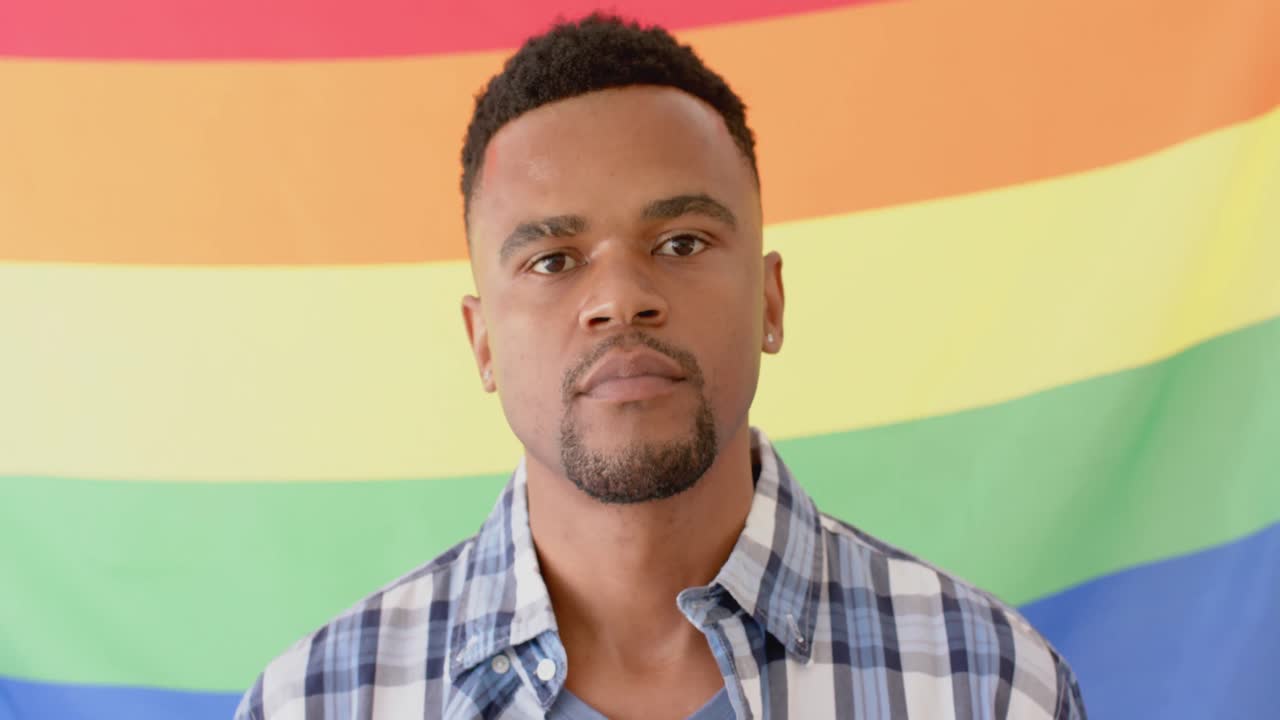 retrato de un feliz hombre afroamericano sosteniendo la bandera del arco iris lgbt, cámara lenta