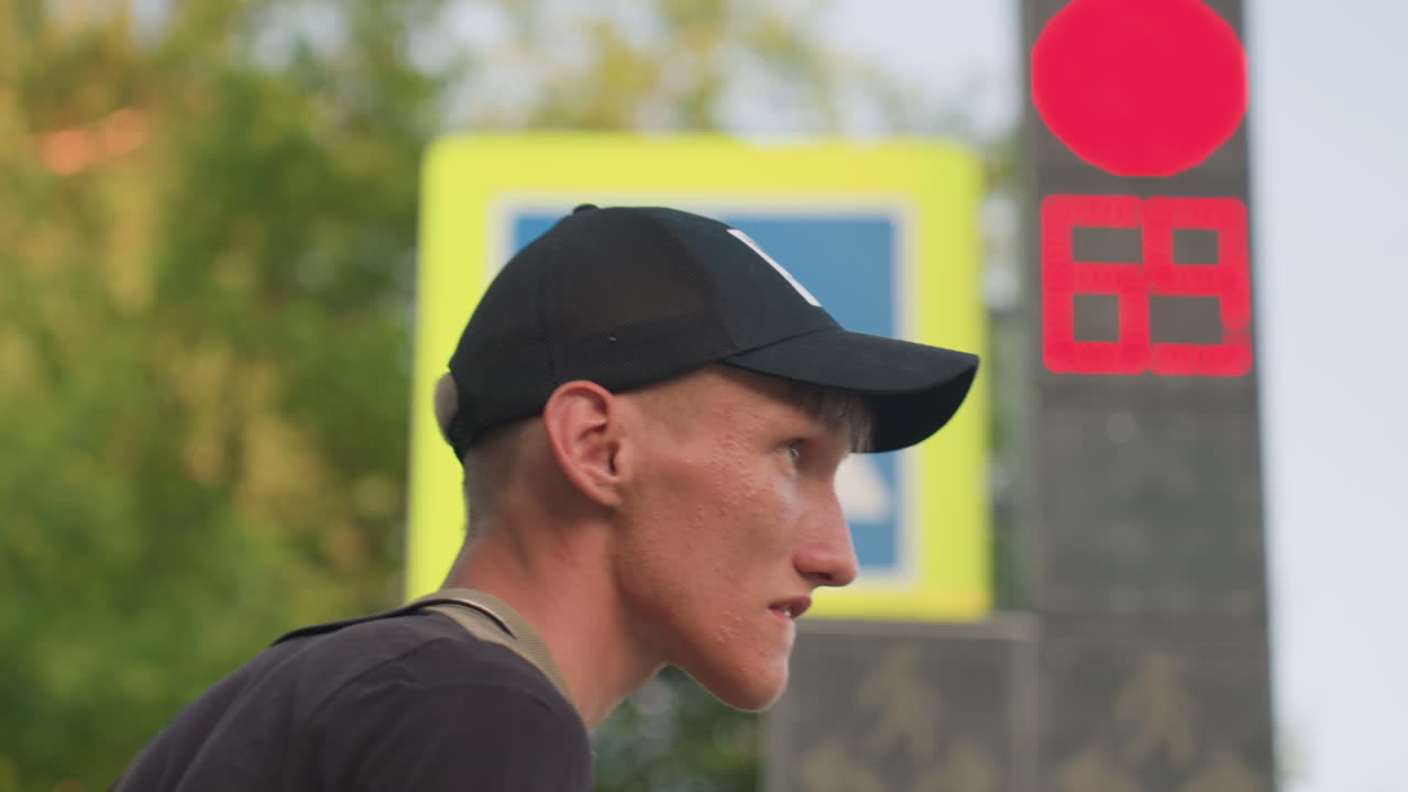 Side Profile Caucasian Man Near Red Pedestrian Signal And Crosswalk Sign, Cap On Head, Focused Gaze, Visible Timer Digits, Summer Trees Behind, Quiet Tension And Resilient Expression Amid Paranoid
