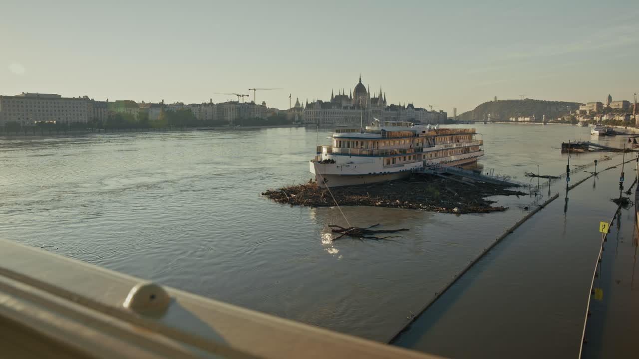 Boat surrounded by debris in flooded river with the Hungarian Parliament in the background, Budapest, Hungary