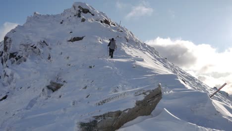 Woman-hiker-alpinist-climbs-a-snowy-peak-at-the-kepler-track-located-in-Fiordland-National-Park,-NZ---Stable-shot