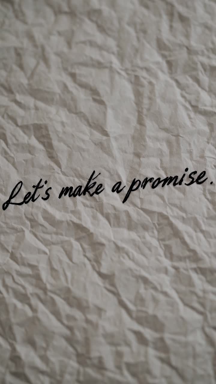 Close-up video shot of crumpled paper with handwritten text 'Let's make a promise,'