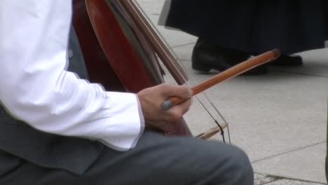 primer plano de un instrumentista folclórico tocando el contrabajo alemán con arco