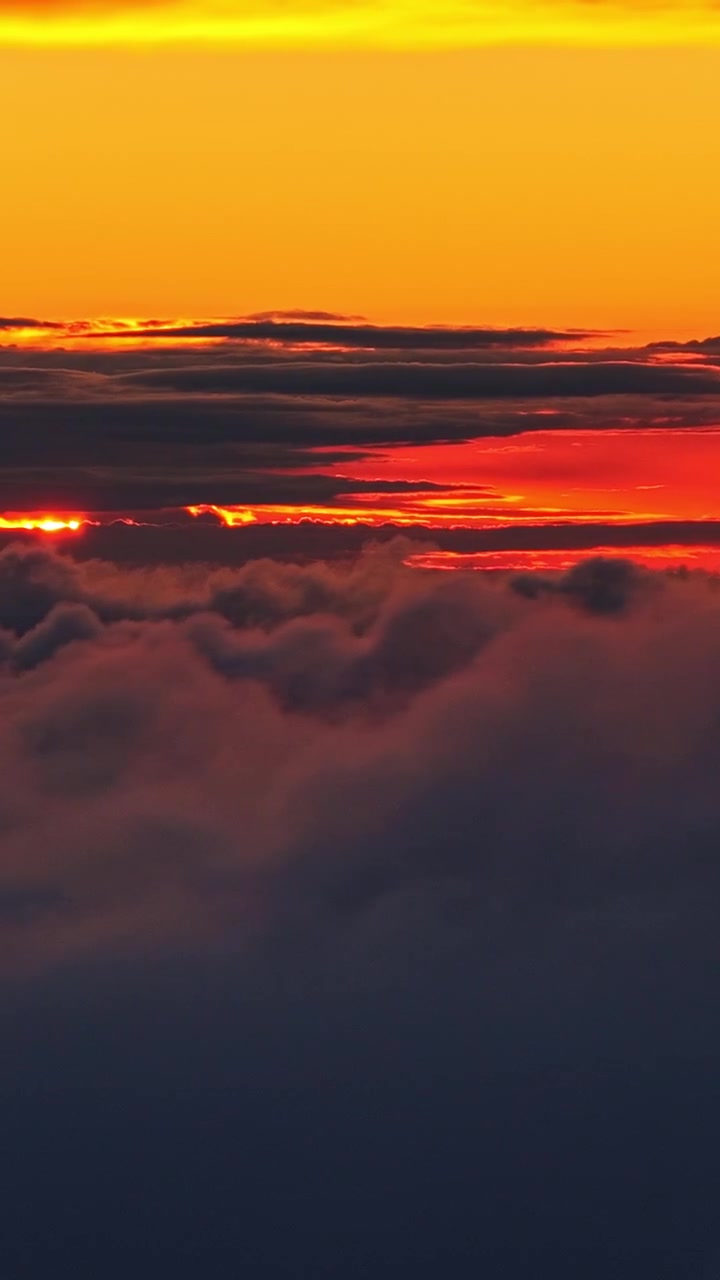 Lebhafter rot-oranger Sonnenuntergangshimmel über Wolken, Hochformat