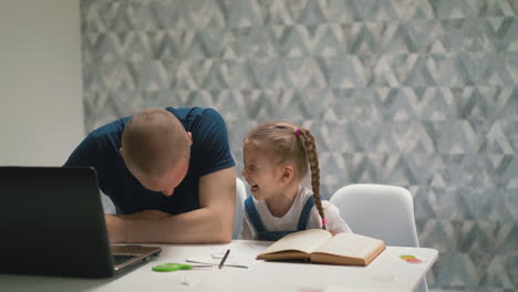 young dad and little daughter laugh at white table in room