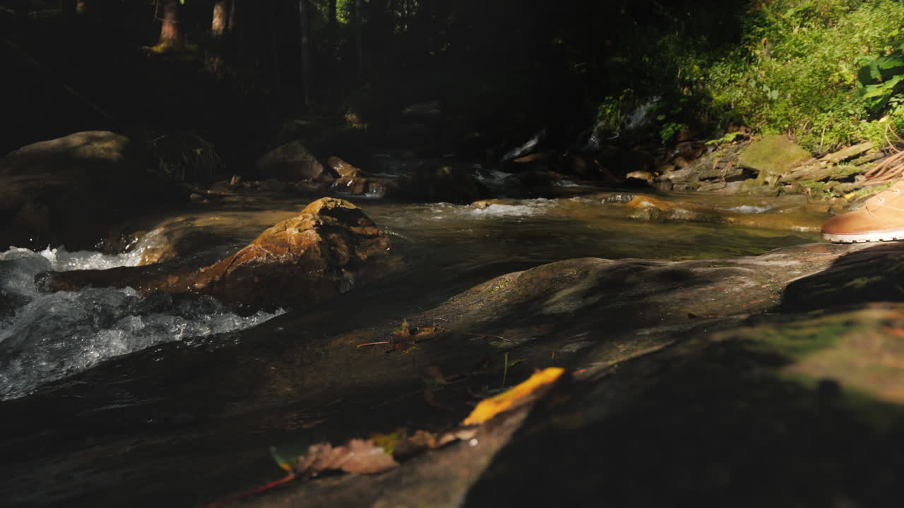 A Traveler In Hiking Boots Passes Through Slippery Stones Only The Legs Are Visible