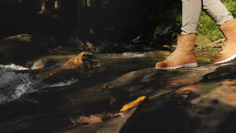 a traveler in hiking boots passes through slippery stones only the legs are visible