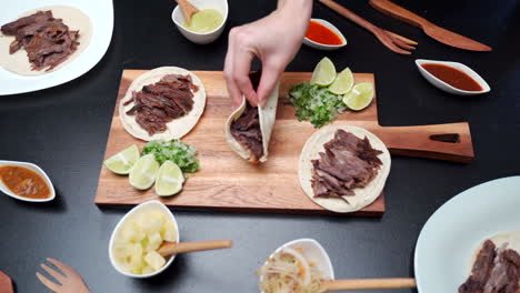 picking up mexican beef tacos of cutting table top view