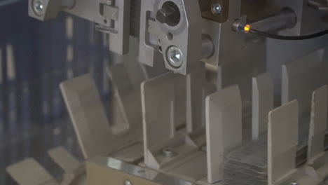 swinging arm machine lowers packaged drug pills onto vertical slots, pan down