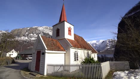 caminando hacia la antigua iglesia histórica de madera en miniatura en undredal noruega - soleado día de invierno con cielo azul y fondo de paisaje de montaña