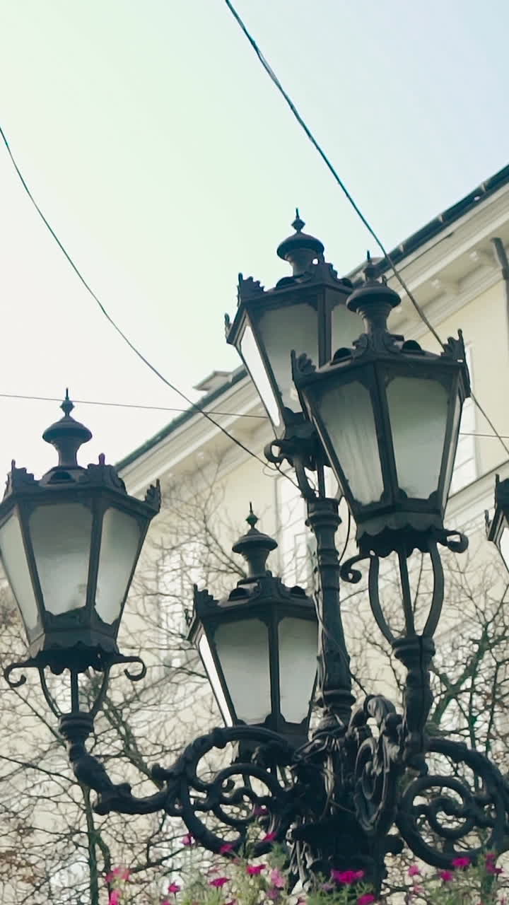 decorative lantern is located in the center of city on the background of urban architecture. Camera motion up. Vertical video