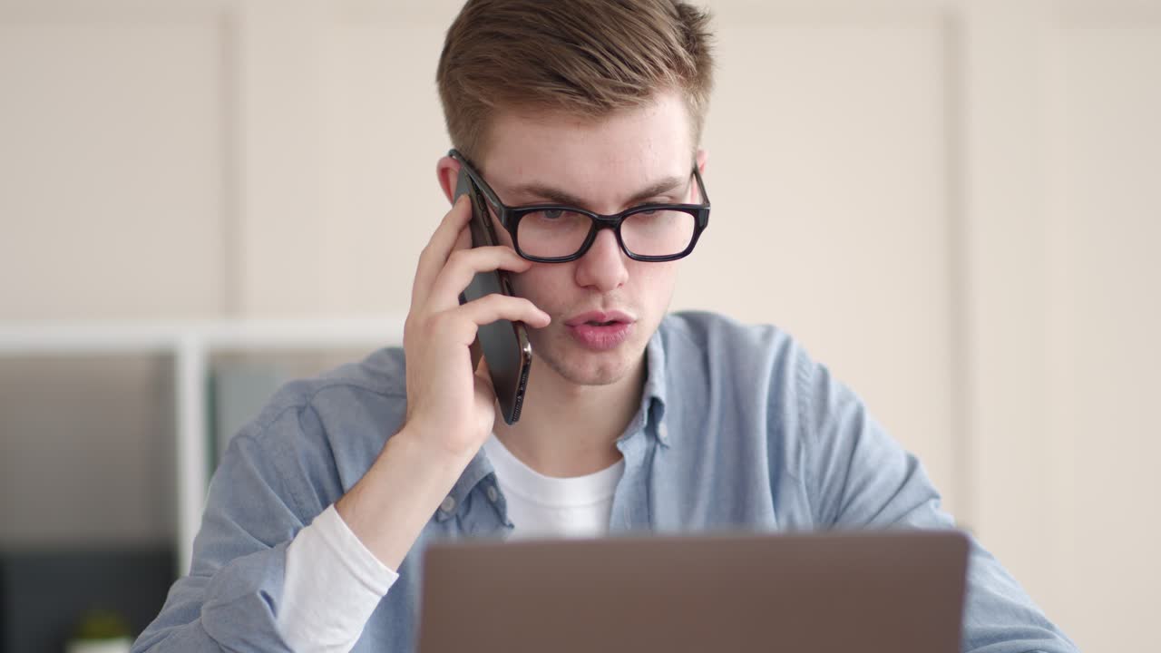 Young man on a phone call at a laptop